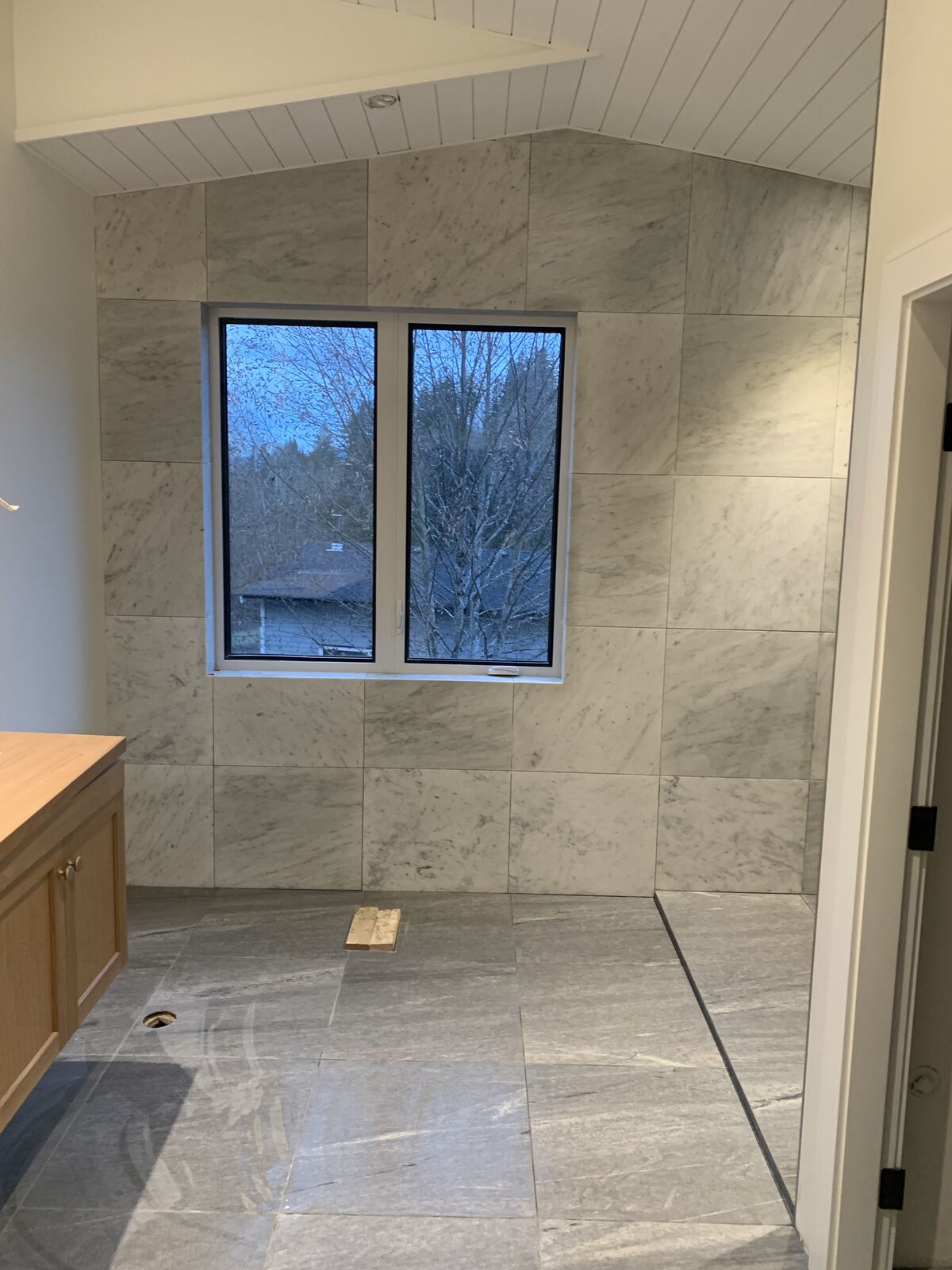 Bathroom tiled floor to ceiling in carrara-look porcelain