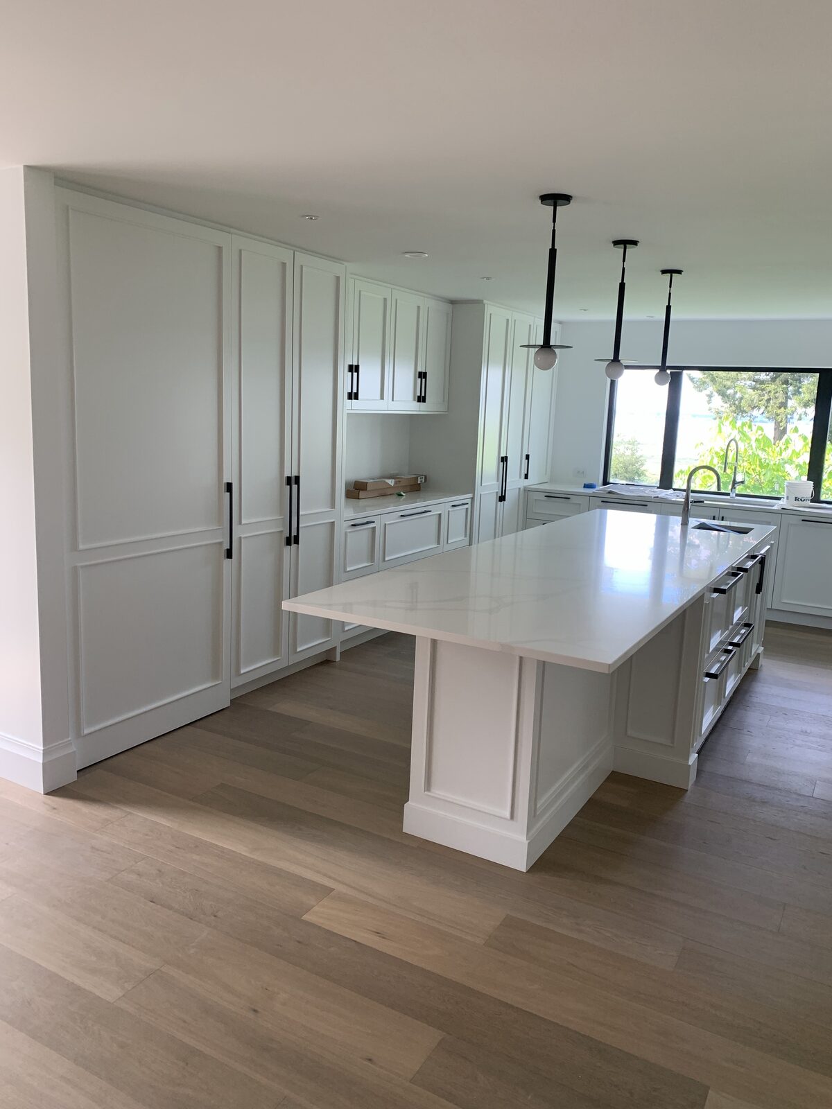 Wide-plank flooring running through a white kitchen