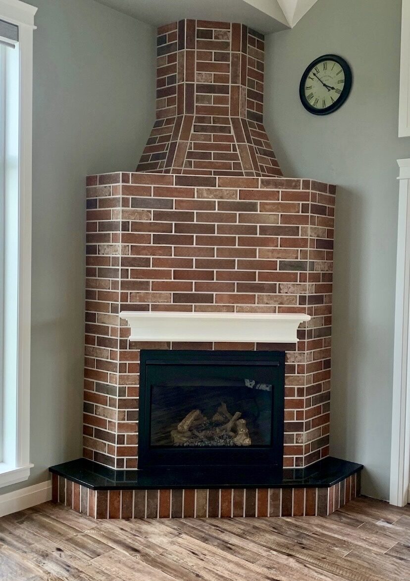 Corner brick fireplace with mantel and tiled hearth