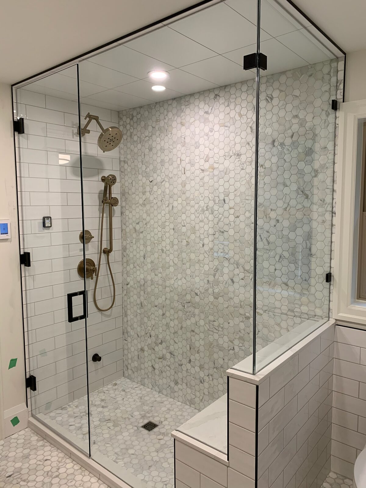 Frameless corner shower enclosure with a mosaic feature wall and bench