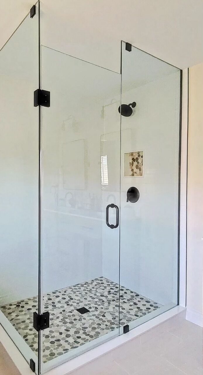 Frameless corner glass enclosure over a pebble mosaic floor