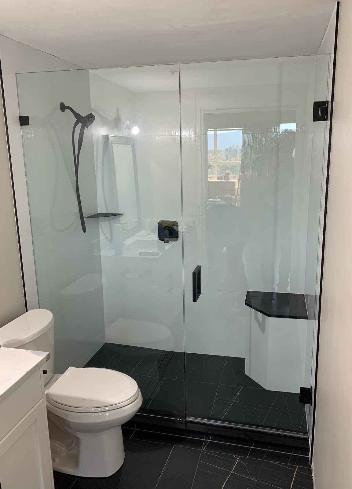 Frameless glass enclosure in a white ensuite with a bench