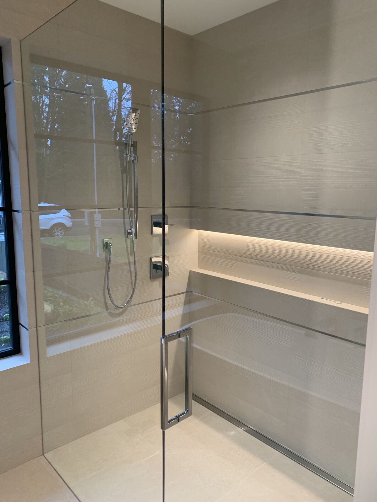 Linen-look tiled shower with a lit niche and bench