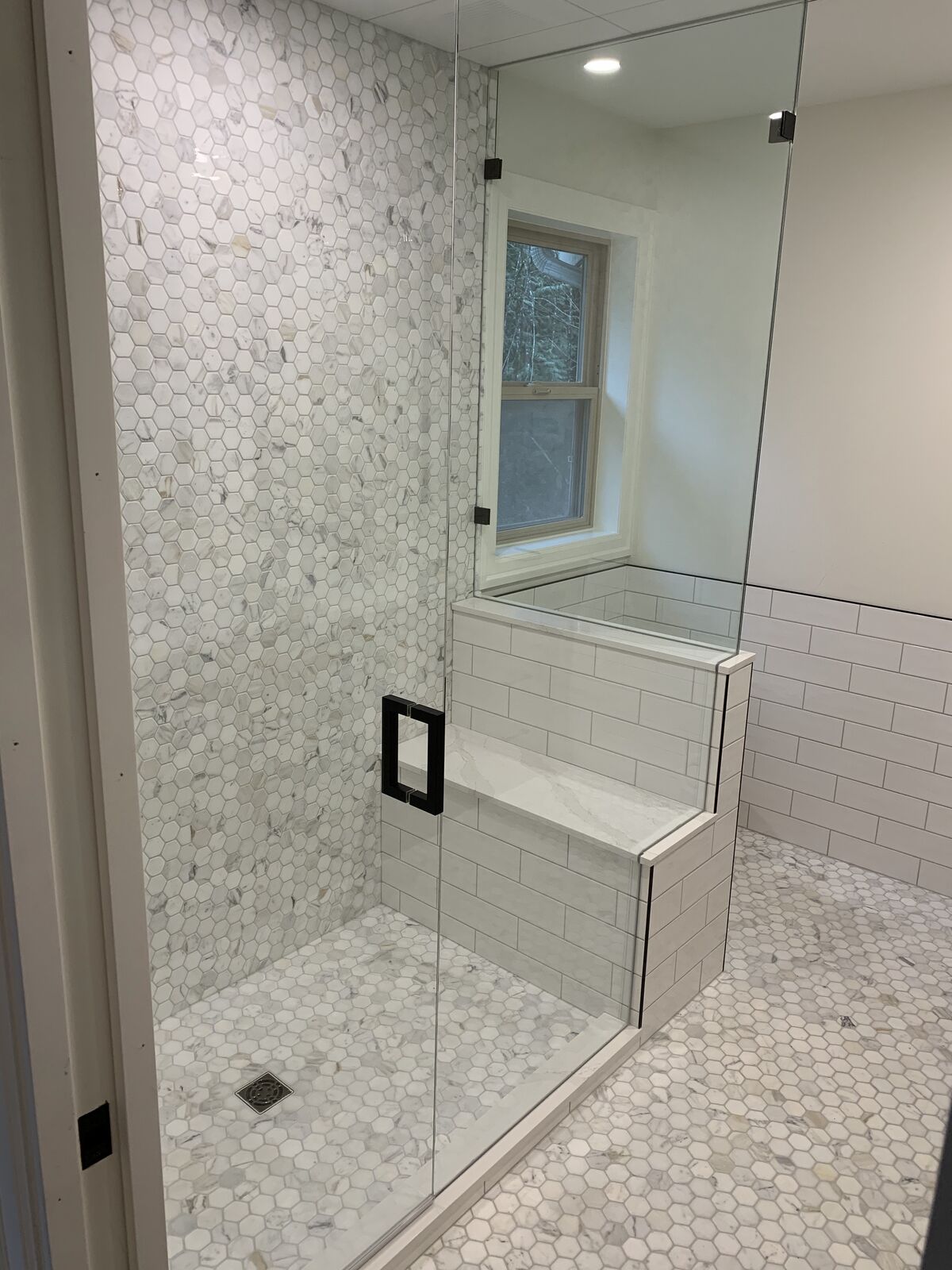 Hex mosaic shower with a bench under the window