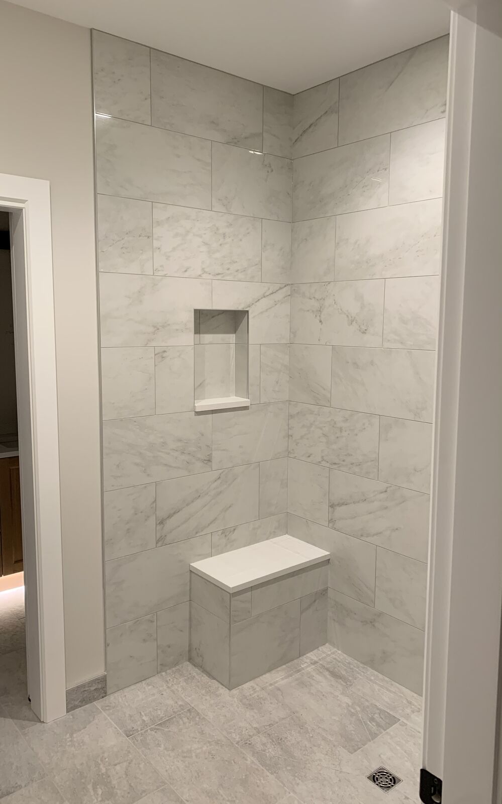 Marble-look shower with a built-in bench and niche