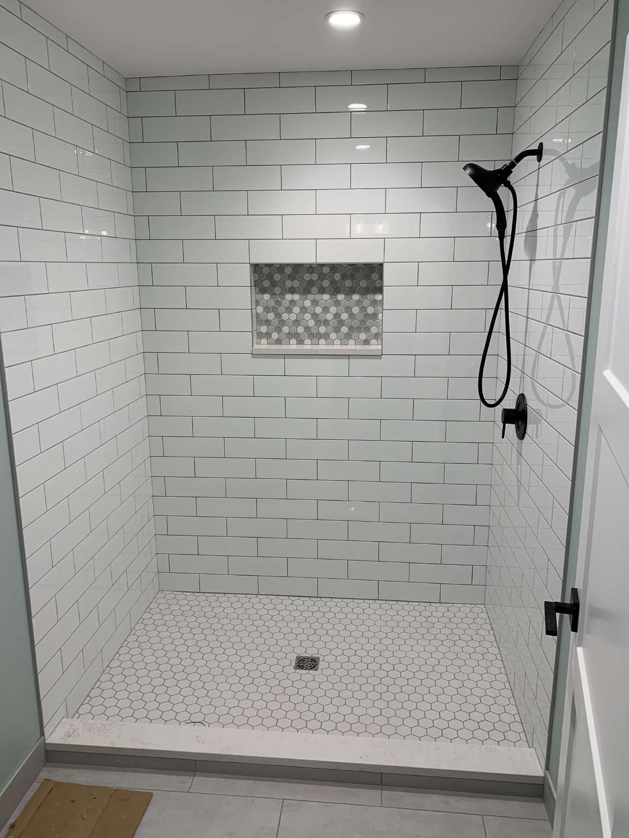 Walk-in tiled shower with mosaic niche